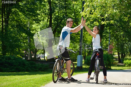 Image of Happy couple riding bicycle outdoors