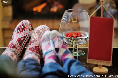 Image of Young romantic couple sitting and relaxing in front of fireplace