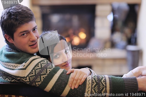 Image of Young romantic couple sitting and relaxing in front of fireplace