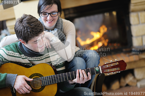 Image of Young romantic couple sitting on sofa in front of fireplace at h