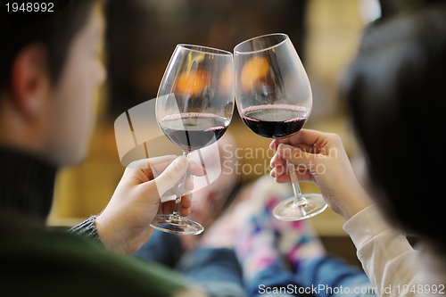 Image of Young romantic couple sitting on sofa in front of fireplace at h