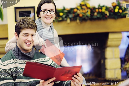 Image of Young romantic couple sitting and relaxing in front of fireplace