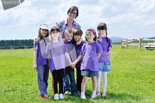 Image of happy kids group with teacher in nature