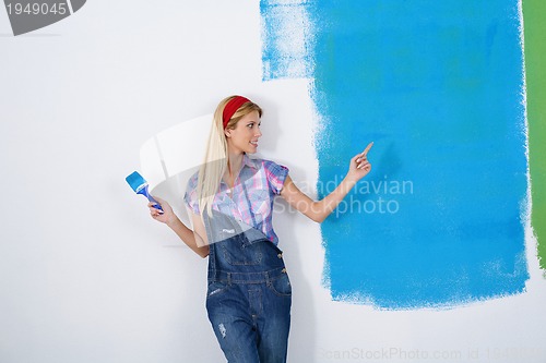 Image of happy smiling woman painting interior of house