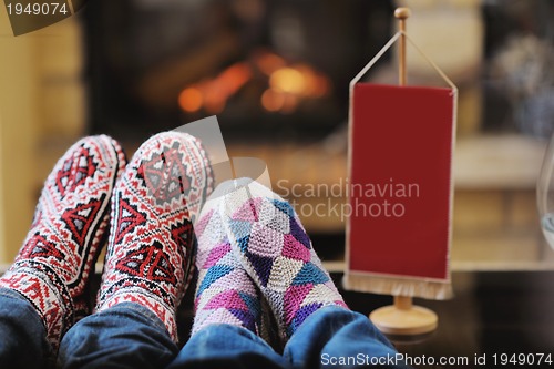 Image of Young romantic couple sitting and relaxing in front of fireplace