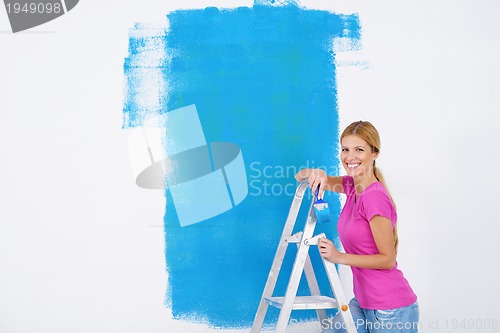 Image of happy smiling woman painting interior of house