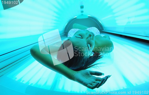 Image of Beautiful young woman tanning in solarium