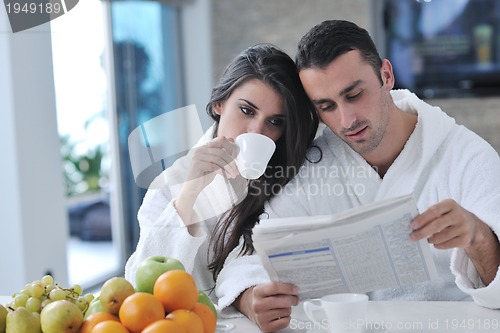 Image of Happy couple reading the newspaper in the kitchen at breakfast
