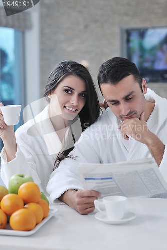 Image of Happy couple reading the newspaper in the kitchen at breakfast
