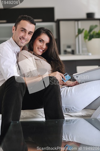 Image of joyful couple relax and work on laptop computer at modern home