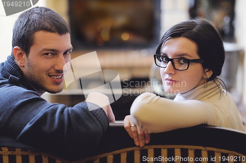 Image of Young romantic couple sitting and relaxing in front of fireplace