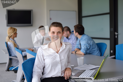 Image of business woman with her staff in background at office