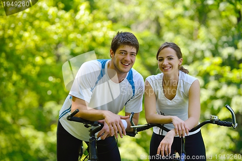 Image of Happy couple riding bicycle outdoors