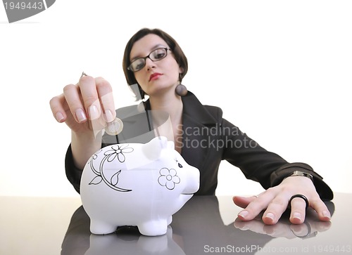 Image of business woman putting money coins in piggy bank