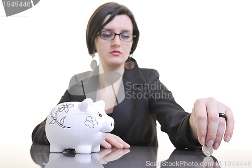 Image of business woman putting money coins in piggy bank