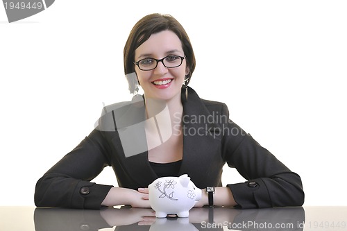 Image of business woman putting money coins in piggy bank