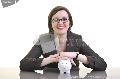 Image of business woman putting money coins in piggy bank