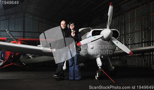 Image of happy young couple posing in front of private airplane