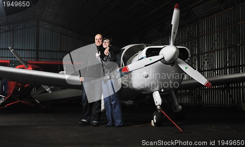 Image of happy young couple posing in front of private airplane