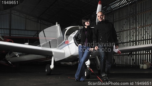 Image of happy young couple posing in front of private airplane