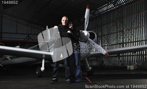 Image of happy young couple posing in front of private airplane