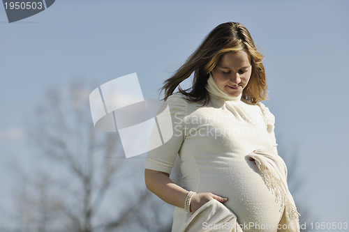 Image of happy young pregnant woman outdoor