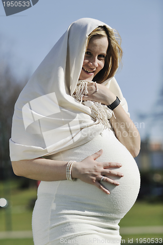 Image of happy young pregnant woman outdoor