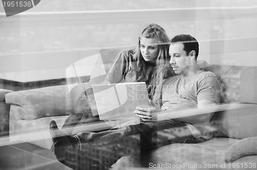 Image of happy couple have fun and work on laptop at home on red sofa