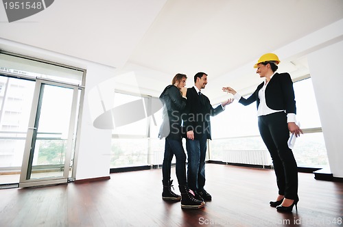 Image of happy young couple buying new home with real estate agent