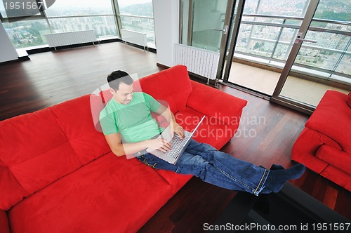 Image of man relaxing on sofa and work on laptop computer