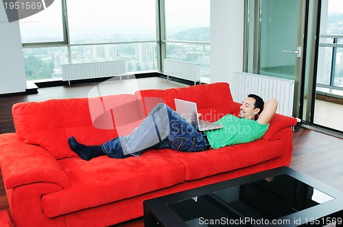 Image of man relaxing on sofa and work on laptop computer