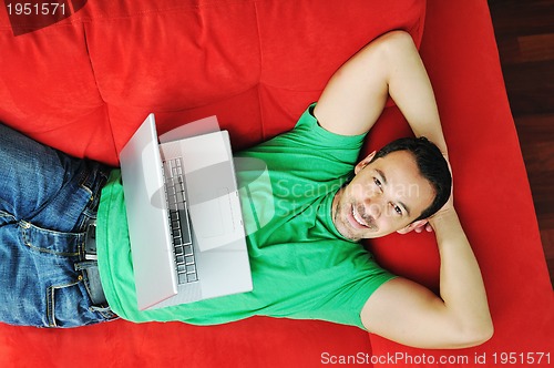 Image of man relaxing on sofa and work on laptop computer