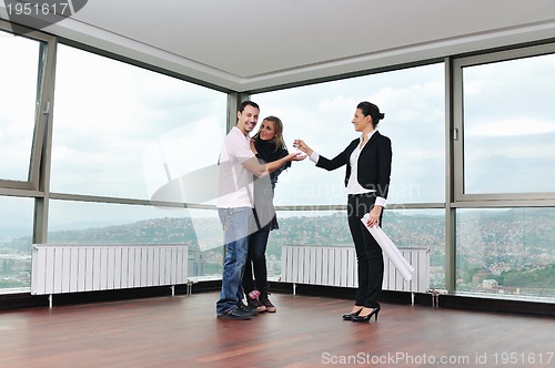Image of happy young couple buying new home with real estate agent
