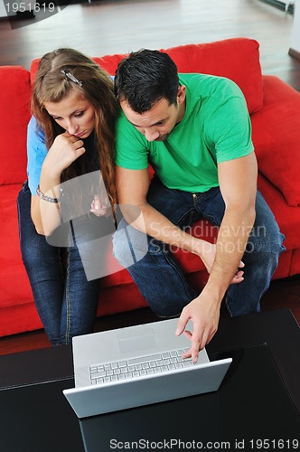 Image of happy couple have fun and work on laptop at home on red sofa