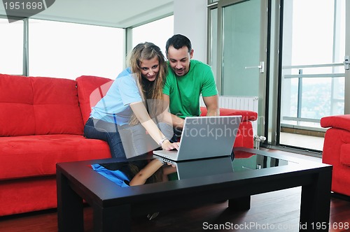 Image of happy couple have fun and work on laptop at home