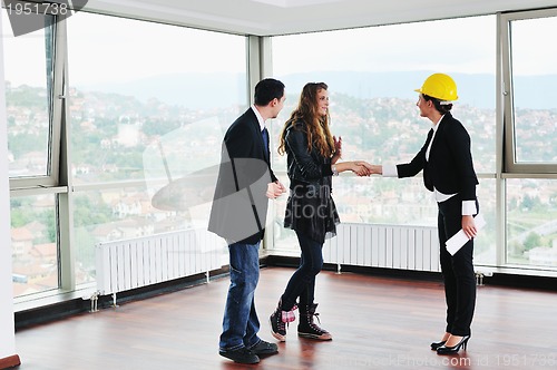 Image of happy young couple buying new home with real estate agent