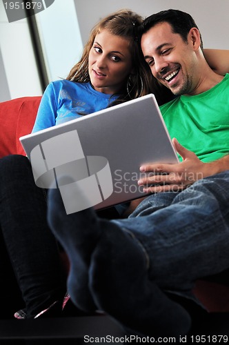 Image of happy couple have fun and work on laptop at home