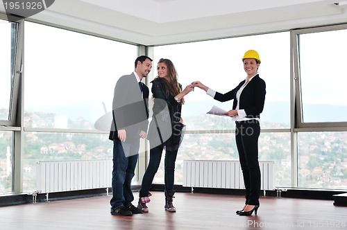 Image of happy young couple buying new home with real estate agent