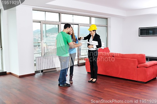 Image of happy young couple buying new home with real estate agent