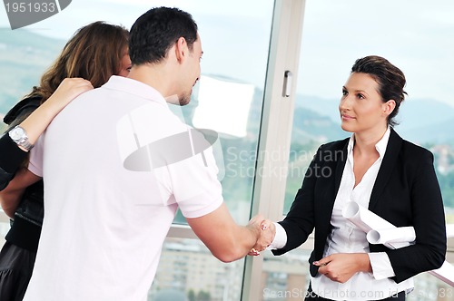 Image of happy young couple buying new home with real estate agent