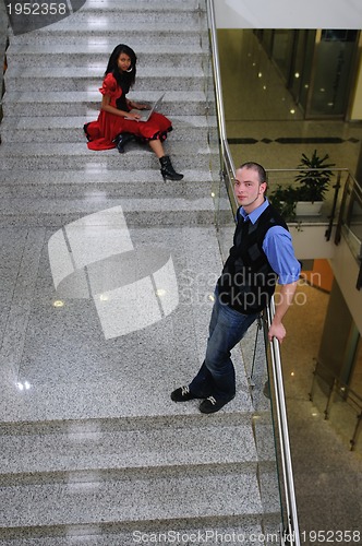 Image of young business man standing on stairs and hold laptop