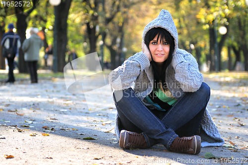 Image of brunette Cute young woman  sitting  in nature