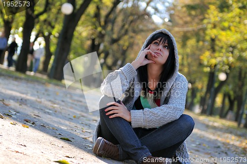 Image of Cute young woman sitting outdoors in nature