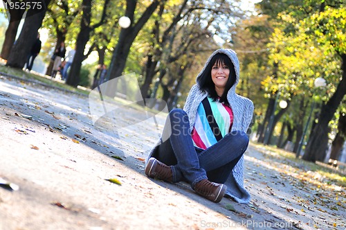 Image of brunette Cute young woman  sitting  in nature
