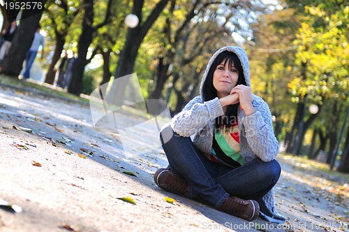 Image of brunette Cute young woman  sitting  in nature