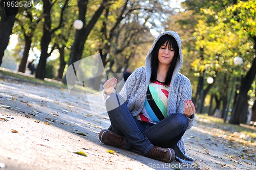 Image of brunette Cute young woman  sitting  in nature