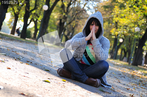 Image of Cute young woman sitting outdoors in nature