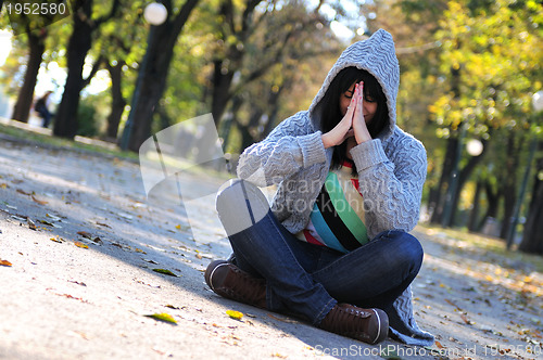 Image of Cute young woman sitting outdoors in nature