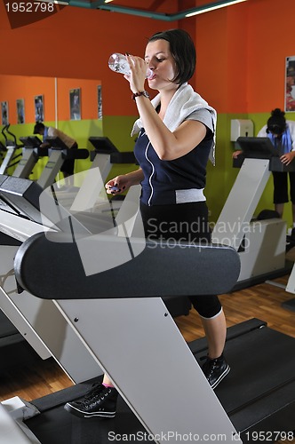 Image of Young woman drinking water while working out