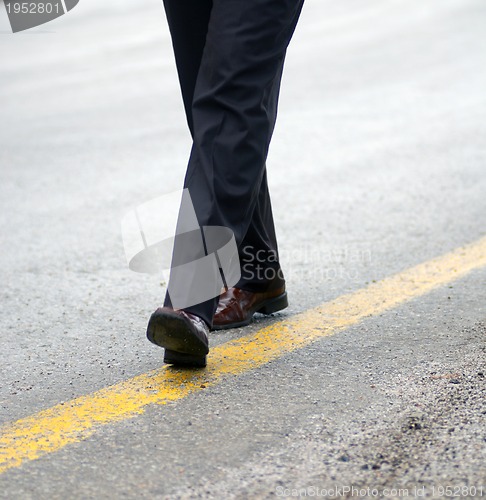 Image of .businessman walking on yellow line